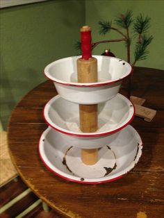 three white bowls stacked on top of each other with a red candle sticking out of them