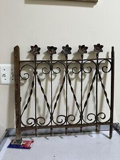 an old iron fence with four flowers on it and a sign hanging above the gate