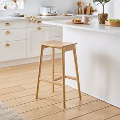 a white kitchen with wooden stools and an island in front of the countertop