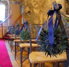 a row of chairs with wreaths tied to them on the back of each chair