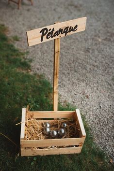 a wooden crate with metal balls in it and a sign that says petangue