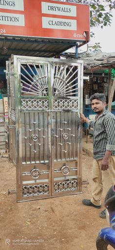 a man standing in front of a metal gate with intricate designs on the top and sides