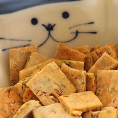 a bowl full of crackers with a cat's face painted on the side