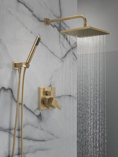 a shower head with thermostaer and hand held shower faucet in front of a marble wall