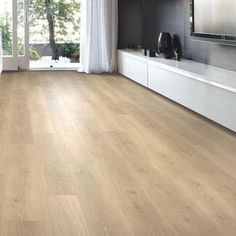 an empty living room with wood floors and white curtains on the window sill,