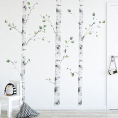 a white room with trees painted on the wall and a black and white chair next to it