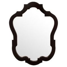 a mirror that is sitting on top of a white wall and has an ornate frame around it