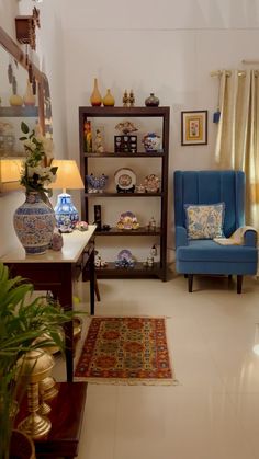 a living room with two blue chairs and a rug in front of a book shelf