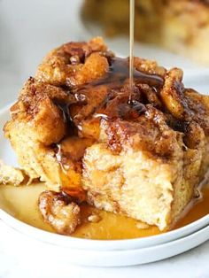 a piece of bread pudding being drizzled with caramel sauce on a white plate