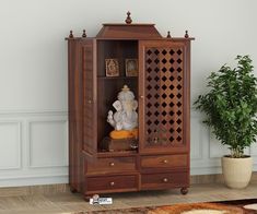 a wooden cabinet with an elephant figurine in the front and a potted plant behind it