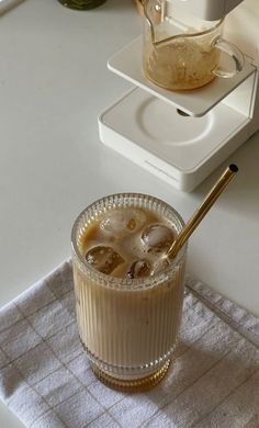 a glass filled with liquid sitting on top of a counter next to a blender