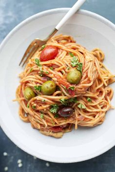 a white bowl filled with pasta and olives