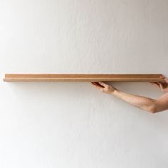 a person holding up a wooden plank on the wall