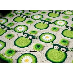 a crocheted blanket with green and white flowers