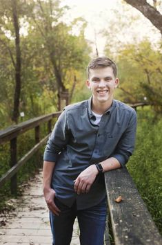 a young man standing on a wooden bridge