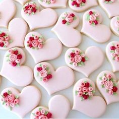 heart shaped cookies decorated with pink and red flowers on a white tablecloth covered in icing