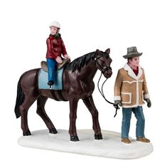 two figurines of people riding horses and one is holding the reins to another horse