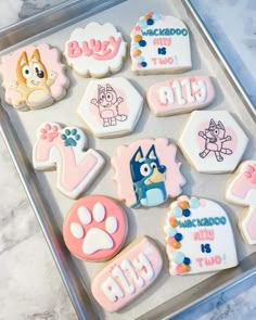 decorated cookies in the shape of dogs and cats on a cookie sheet with pink icing