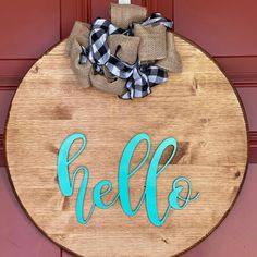 a wooden sign with the word hello painted on it and a bow tied to it