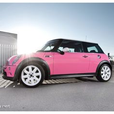 a pink mini cooper parked in a parking lot