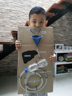 a young boy holding up a cardboard box with an image of a man's face on it