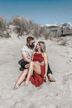 a man and woman are sitting on the sand