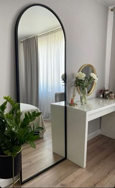 a mirror sitting on top of a wooden floor next to a table with a potted plant