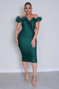 a woman wearing a green dress with ruffles on the shoulders and one shoulder