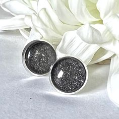 This eye and light catching earring set features silver plated stud earrings filled with sparkling iron filings and topped with a glass cabochon. Celebrate 6 years of marriage in style! Earrings: approx 12mm diameter. Boxed in a luxury box with magnetic closure.  All of our jewellery boxes are eco friendly and FSC certified. See our complete range of Iron (6th) Anniversary Gifts here: https://www.etsy.com/uk/shop/HandmadeAnniversary?ref=seller-platform-mcnav&section_id=39413722 NOTE: All of our items are handmade and therefore slight variations may occur.  Colours may appear different depending on your screen settings. Shipping We offer free shipping to the UK.  All items are posted by Royal Mail 2nd Class and, if ordered by 3pm Monday to Friday, will be with the Post Office by 5pm on the Gift Silver Nickel Free Clip-on Earrings, Minimalist Silver Sparkling Earrings, Minimalist Silver Earrings With Sparkling Details, Silver Glitter Round Earrings, Adjustable Silver Glitter Jewelry, Sparkling Silver Earrings For Gift, Glitter Round Jewelry As Gift, Round Glitter Jewelry As Gift, Round Glitter Jewelry For Gifts