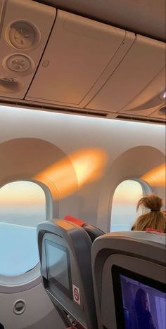 the inside of an airplane with two people watching television