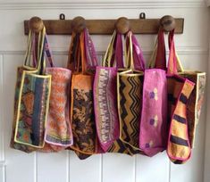 multicolored bags hanging from wooden hooks on white wall with wood coat hanger