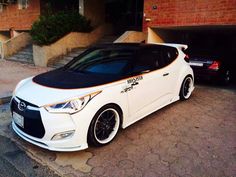 a white and black car parked in front of a brick building next to another car