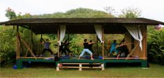 a group of people doing yoga in front of a gazebo with white drapes