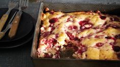 a close up of a cake in a pan on a table with utensils