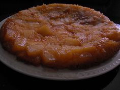 a pineapple upside down cake on a white plate with a black table top and dark background