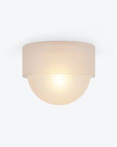 a white light that is on the side of a wall mounted fixture with a round glass shade