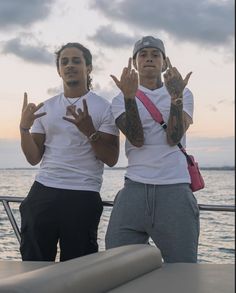 two men standing next to each other with their hands in the shape of peace signs