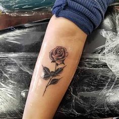 a woman's arm with a rose tattoo on the left side of her arm