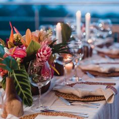 the table is set with place settings and flowers in vases, candles, and napkins