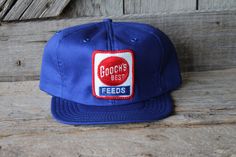 I recently found a bunch of unworn new old stock caps from the 1980s through 1990s, and will be unloading several of these here in the etsy shop.  This listing is for an unused vintage Gooch's Best brand feed company advertising trucker cap.  It has an embroidered patch featuring the company's logo on an all blue hat with a snapback adjustable closure.   It is in very good unworn condition.  The inner foam lining is still fully intact.  This is a great vintage deadstock cap, and was made by Snap-A-Tab in the USA. Livestock Feed, Vintage Trucker Hats, Blue Hat, Best Brand, Embroidered Patches, Trucker Cap, Patch Logo, Trucker Hat, Caps Hats