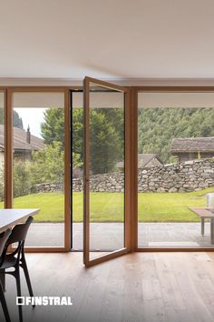 an open living room with sliding glass doors leading to a patio and stone wall in the background