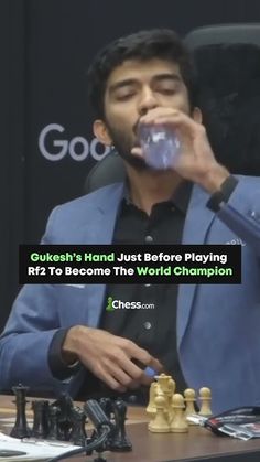 a man sitting at a table drinking water from a glass in front of chess pieces