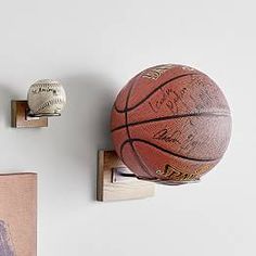 two basketballs are mounted to the wall and one is on a wooden block with hooks