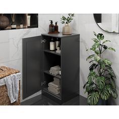 a bathroom with a black cabinet next to a potted plant and towels on the floor