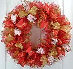 a red and gold mesh wreath hanging on a white door with the word love written on it