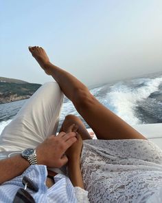 a man and woman are laying on the back of a boat in the water, with their feet up