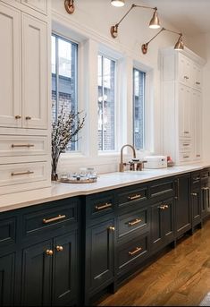 a kitchen with black and white cabinets, gold pulls on the doors and brass fixtures