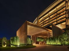 an exterior view of a hotel at night with lights on and trees in the foreground