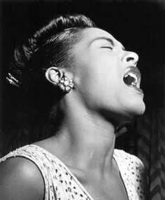 a black and white photo of a woman with her mouth open singing into a microphone