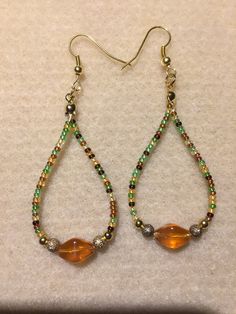 a pair of beaded earrings with glass beads and gold - toned tears